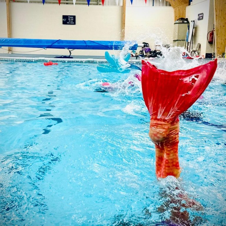 Child performing hand stand in mermaid fin at Oldway-pool-paignton-mermaid-class-children-handstand-orange-monofin
