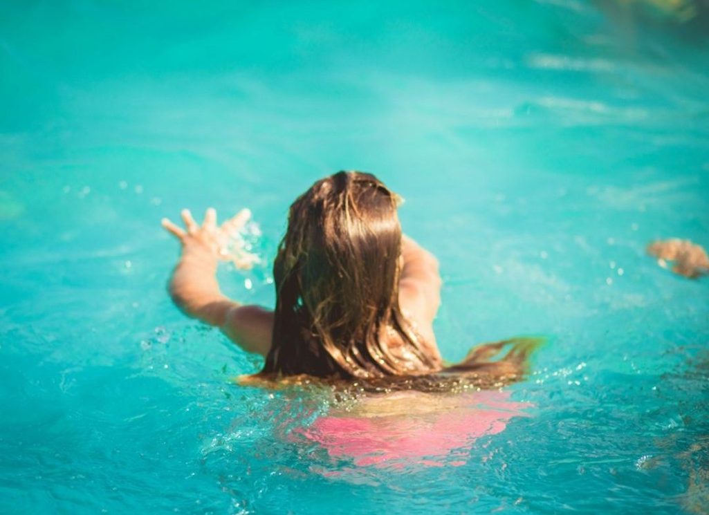 A young girl with arms outstretched over the water, ready to swim at a Mermaids & Bubbles mermaid swimming lesson in South Devo