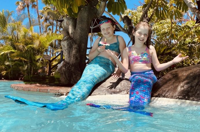 Twin girls wearing mermaid tails during a swim lesson at Mermaids & Bubbles, South Devon